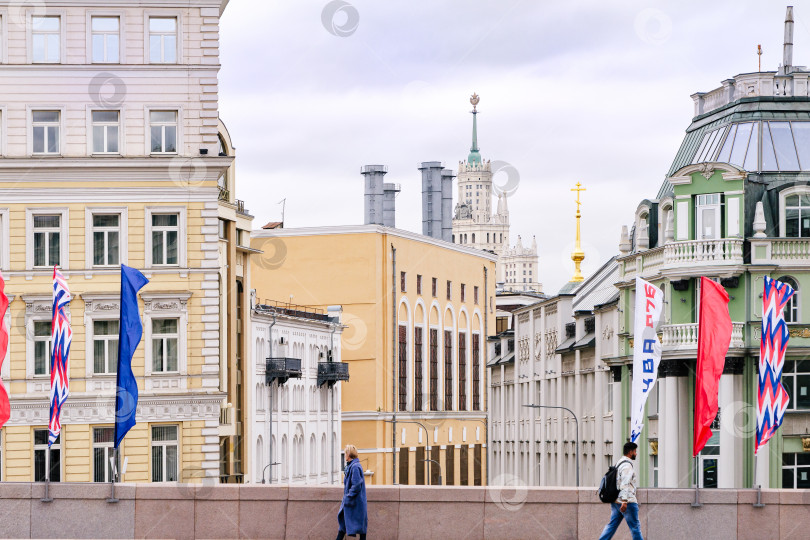 Скачать Москва. Два человека на Большом Москворецком мосту идут на фоне домов разнообразного стиля постройки. фотосток Ozero