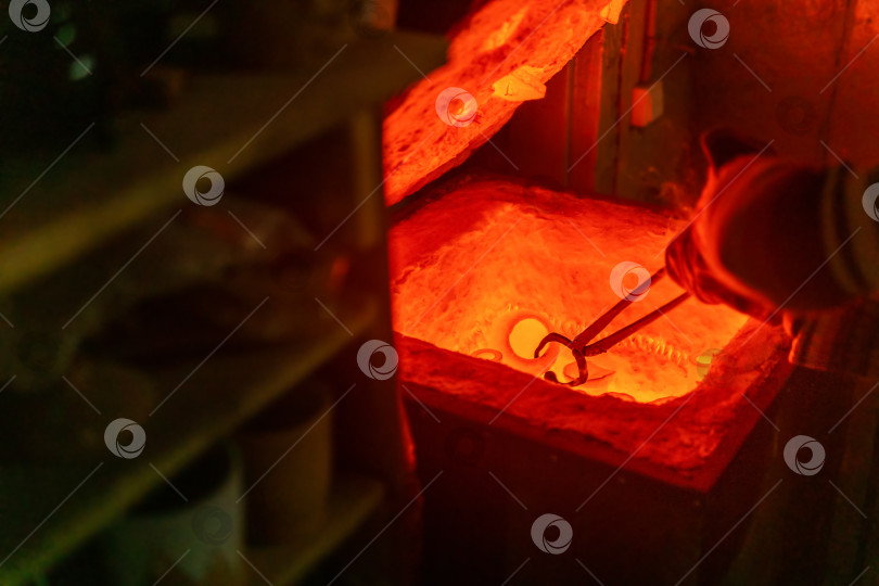 Скачать гончар вынимает глиняную посуду щипцами из раскаленной докрасна электрической муфельной печи для обжига фотосток Ozero