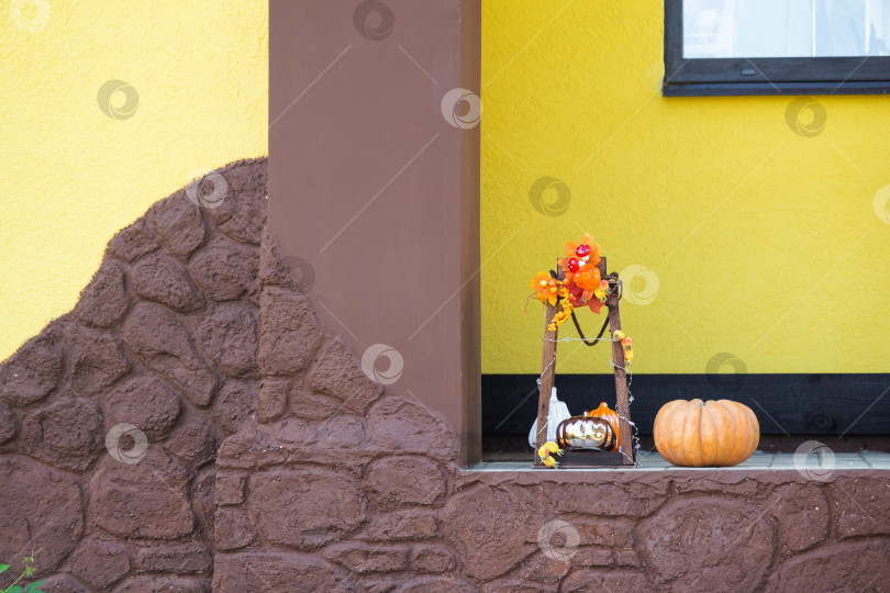 Скачать Осенний декор на крыльце дома, снаружи во дворе из тыквы, фонаря, гирлянд, шляп, фонаря Джека. Вечеринка на Хэллоуин, осеннее настроение, праздник урожая фотосток Ozero