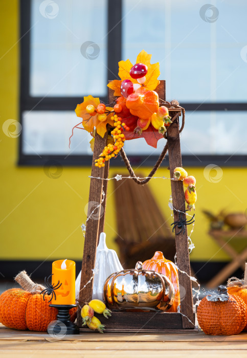 Скачать Осенний декор на крыльце дома, снаружи во дворе из тыквы, фонаря, гирлянд, шляп, фонаря Джека. Вечеринка на Хэллоуин, осеннее настроение, праздник урожая фотосток Ozero