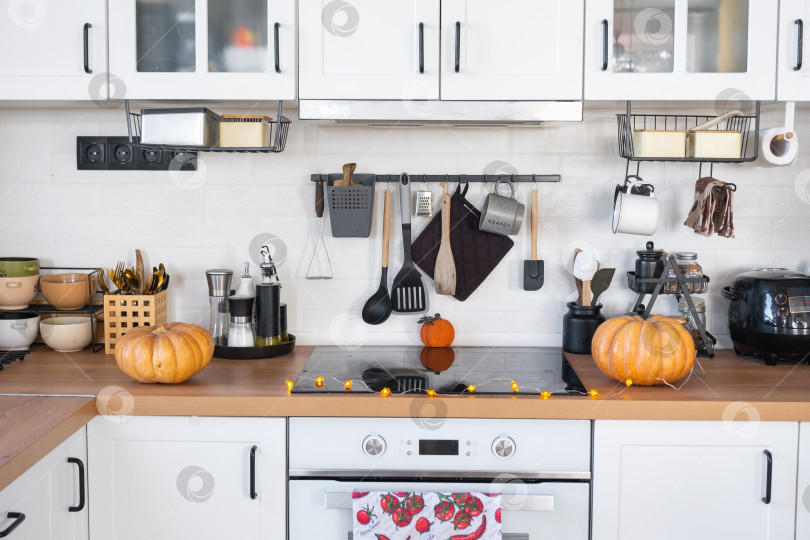 Скачать Декор белой классической кухни тыквами на Хэллоуин и сбор урожая. Осеннее настроение в домашнем интерьере, современный стиль лофт. фотосток Ozero