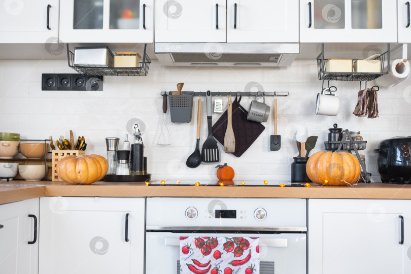 Скачать Декор белой классической кухни тыквами на Хэллоуин и сбор урожая. Осеннее настроение в домашнем интерьере, современный стиль лофт. фотосток Ozero
