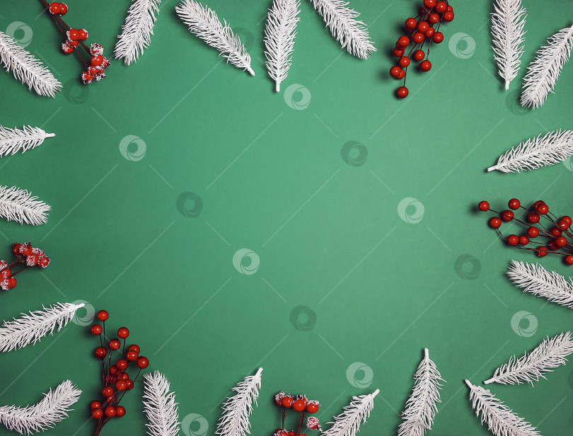 Скачать Рождественская рамка из белых еловых веток и красных ягод на зеленом фоне. фотосток Ozero