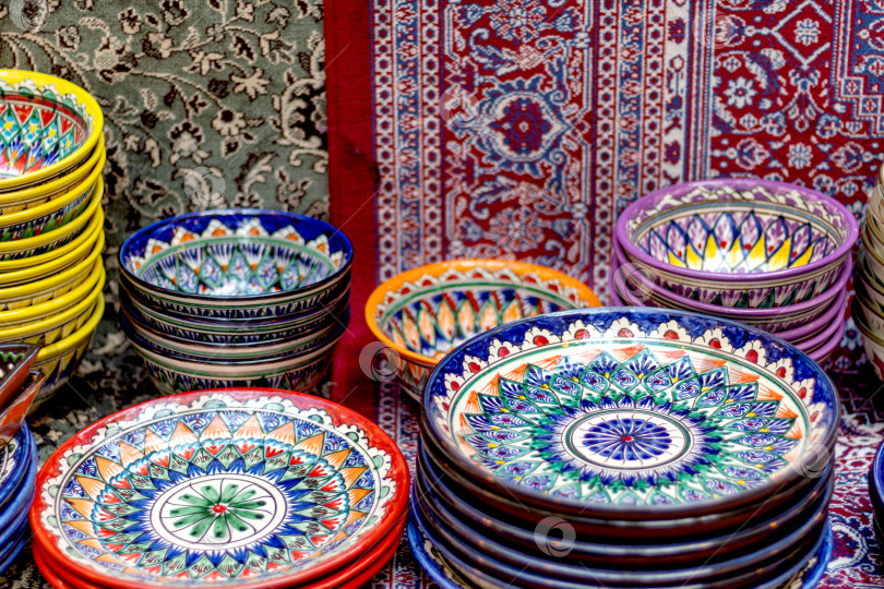 Скачать Богато расписанные красочные восточные блюда, керамика и ковры в витрине рынка. Великий шелковый путь фотосток Ozero