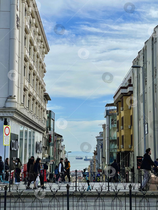 Скачать 14 апреля 2023 года - Стамбул, Турция: городская жизнь, люди на улице и море с кораблями в конце улицы фотосток Ozero