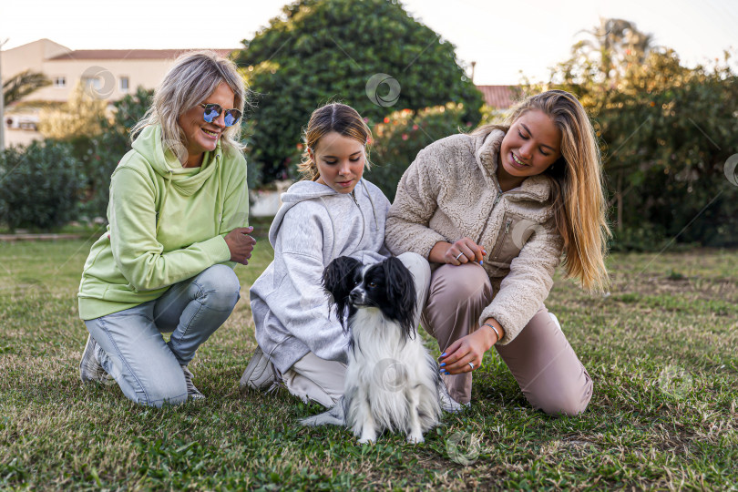 Скачать Мать и дочери играют с собакой в парке фотосток Ozero