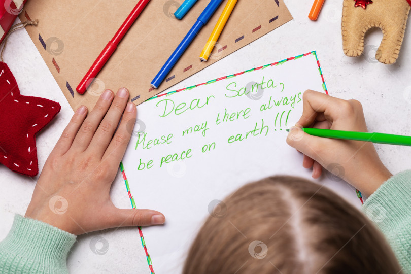 Скачать Ребенок пишет письмо Деду Морозу с просьбой о мире во всем мире фотосток Ozero