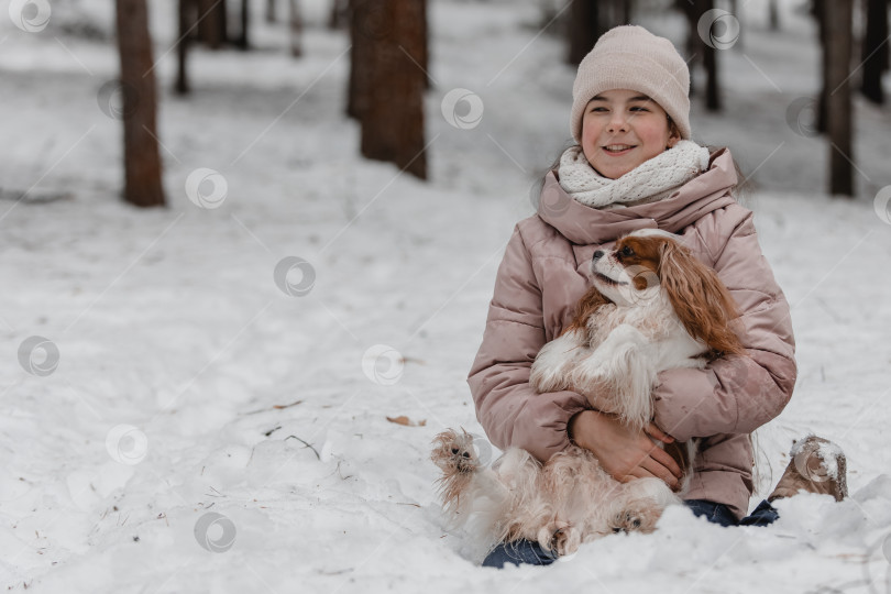 Скачать Милая девушка играет с собакой в зимнем парке, лесу фотосток Ozero