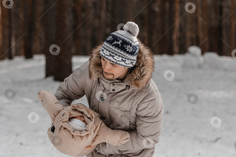 Скачать Папа и малыш прогуливаются по лесу. Папа держит ребенка на руках зимой. Папа и дочь зимой на улице. фотосток Ozero