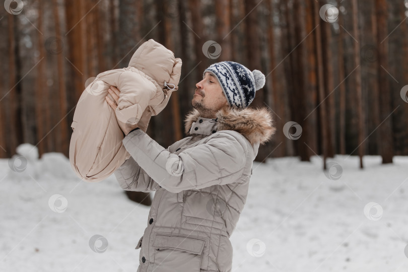 Скачать Папа и малыш прогуливаются по лесу. Папа держит ребенка на руках зимой. Папа и дочь зимой на улице. фотосток Ozero