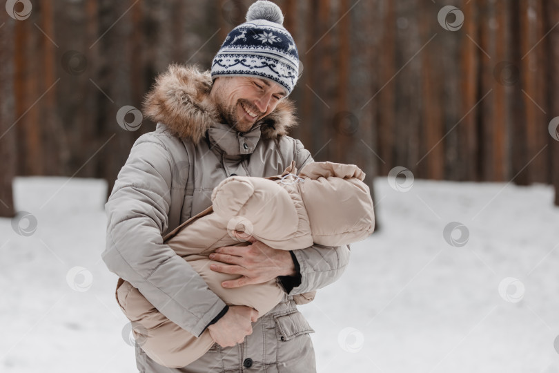 Скачать Папа и малыш прогуливаются по лесу. Папа держит ребенка на руках зимой. Папа и дочь зимой на улице. фотосток Ozero