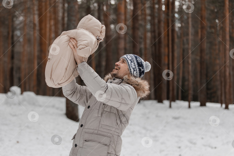 Скачать Папа и малыш прогуливаются по лесу. Папа держит ребенка на руках зимой. Папа и дочь зимой на улице. фотосток Ozero