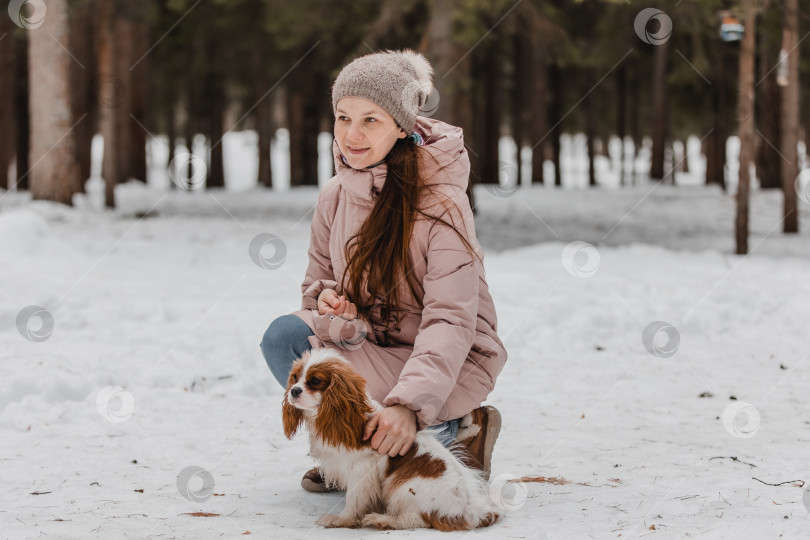 Скачать Симпатичная женщина играет с собакой в зимнем парке, лесу фотосток Ozero