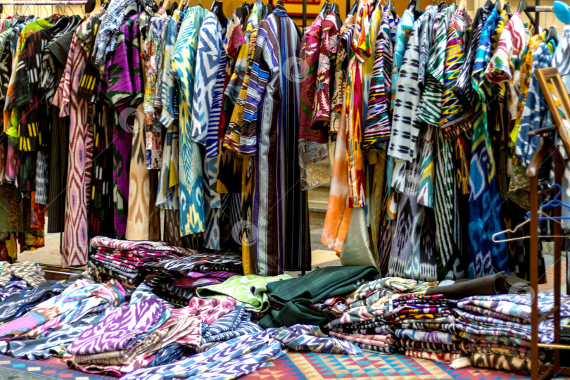 Скачать Яркая узбекская и таджикская национальная одежда. Шелковые платья. Рыночная распродажа. Традиции Востока фотосток Ozero