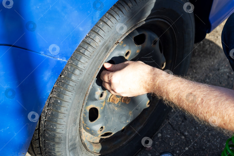 Скачать Мужчина накачивает колесо синего автомобиля фотосток Ozero