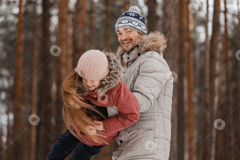 Скачать Отец гуляет со своей маленькой дочерью по зимнему лесу. Счастливая семья папы и маленькой дочери на природе. Концепция дня отца. фотосток Ozero