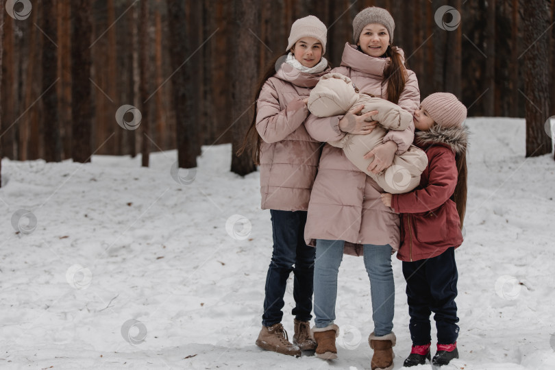 Скачать Семейная зимняя прогулка по лесу. Мать и дочь весело проводят время зимой в лесу в солнечную морозную погоду. Материнские объятия. фотосток Ozero