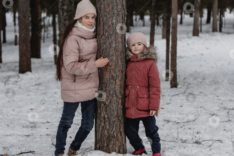 Скачать Две очаровательные молодые девушки весело проводят время вместе в красивом замерзшем парке, лесу. Милые сестрички играют в снежок фотосток Ozero