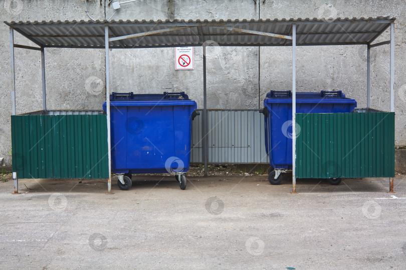 Скачать два синих мусорных бака в зоне сбора мусора. фотосток Ozero