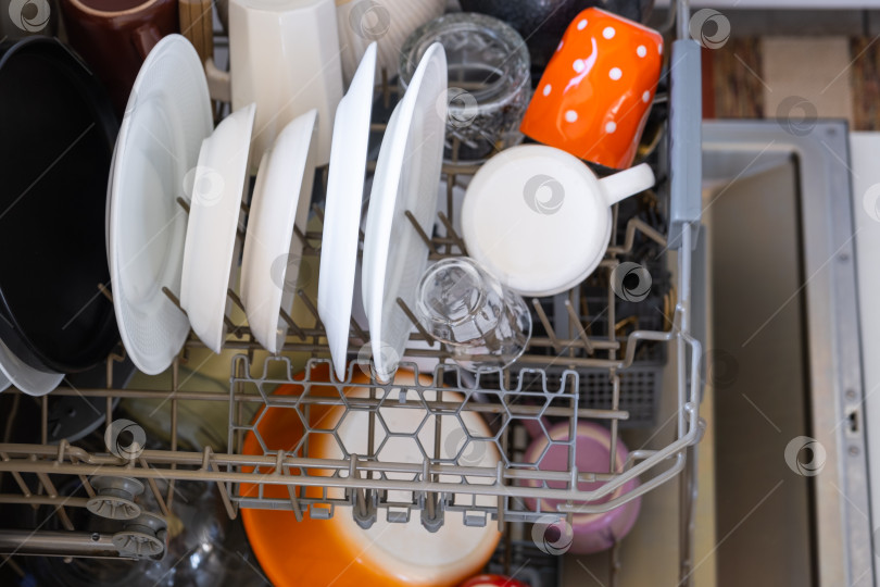 Скачать В посудомоечной машине много грязной посуды. Помощь хозяйке, экономия и экология. Уборка на кухне фотосток Ozero