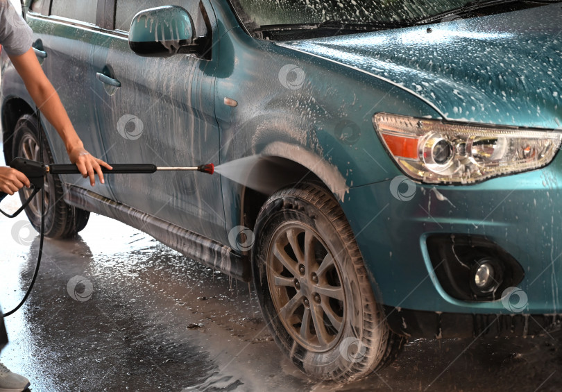 Скачать Чистка автомобиля с использованием активной пены. Женщина моет свою машину на самостоятельной мойке автомобилей фотосток Ozero