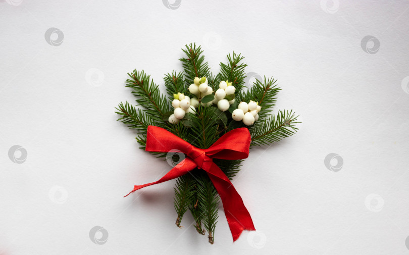 Скачать Рождественский букет с еловыми ветками, красным бантом и белыми ягодами кизила на белом фоне. Рождественская открытка. Тема зимнего праздника. с Новым Годом фотосток Ozero