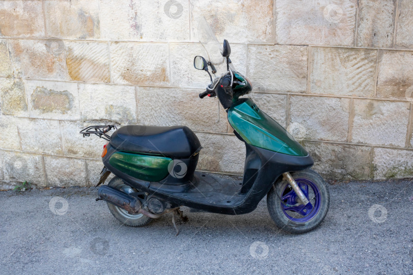 Скачать Зеленый скутер припаркован в переулке у каменной стены. Быстрая доставка фотосток Ozero