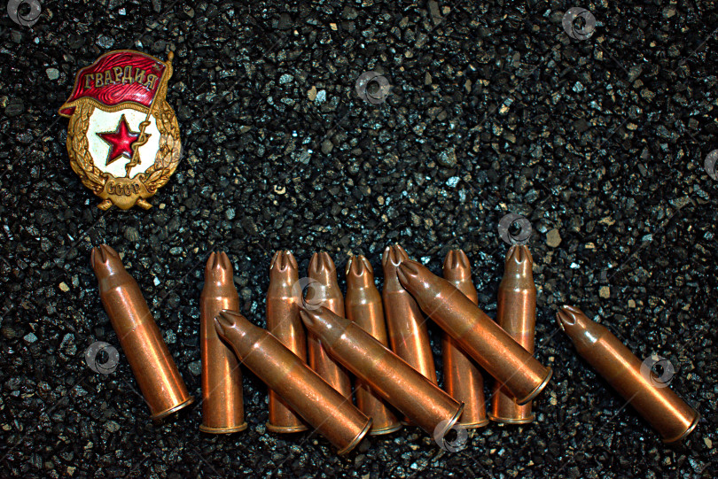 Скачать Нагрудный знак Гвардия и холостые винтовочные патроны на чёрном фоне. фотосток Ozero