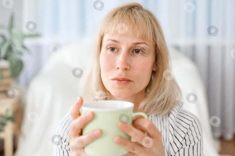 Скачать Молодая женщина сидит дома на диване и пьет чай, съемка в помещении в непринужденном стиле фотосток Ozero
