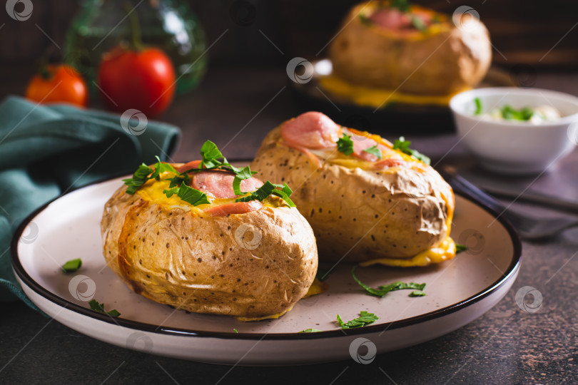 Скачать Запеченный целиком картофель с яйцом, сосисками и зеленью на тарелке фотосток Ozero