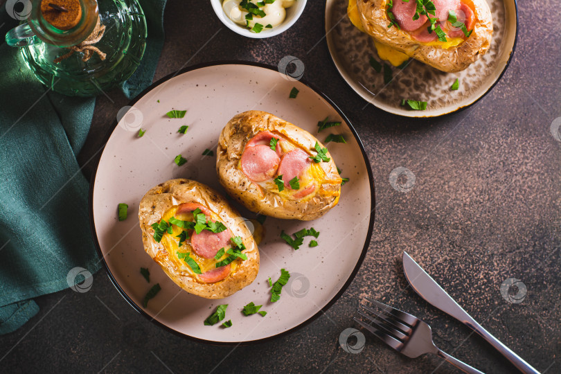 Скачать Запеченный целиком картофель с яйцом, сосисками и зеленью на тарелке вид сверху фотосток Ozero