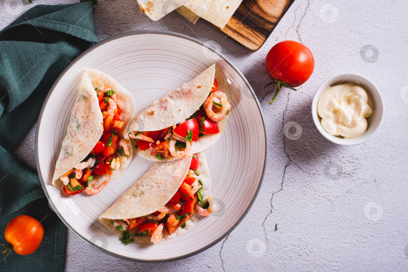 Скачать Вегетарианские мини-тако с помидорами, креветками и зеленью на тарелке на столе вид сверху фотосток Ozero