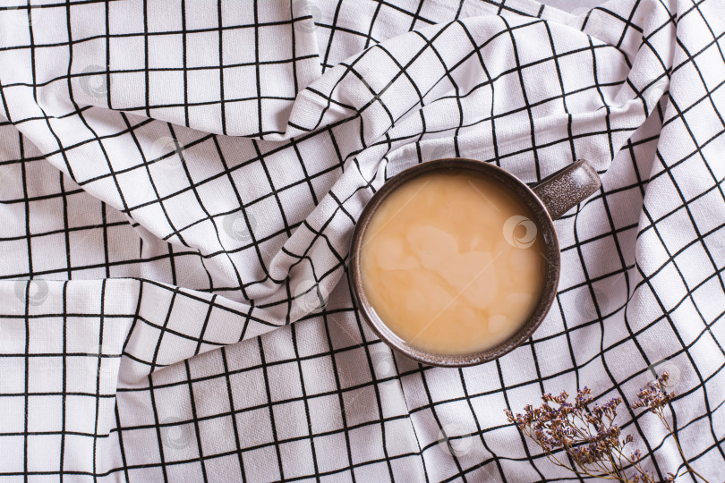 Скачать Концепция замедления жизни. Чашка кофе с молоком на клетчатой мятой ткани вид сверху фотосток Ozero
