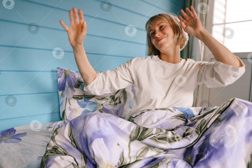 Скачать Красивая молодая женщина потягивается в постели после пробуждения. фотосток Ozero