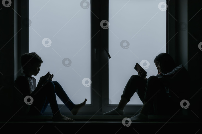 Скачать Маленький мальчик и его сестра сидят у окна фотосток Ozero