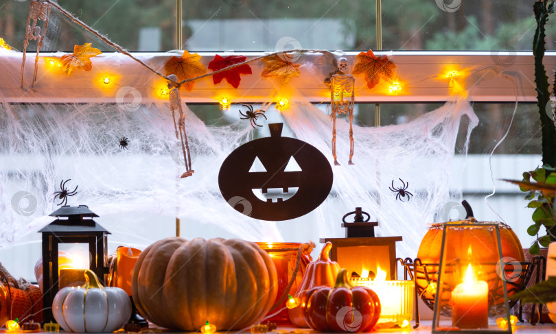 Скачать Праздничный декор дома на подоконнике к Хэллоуину - тыквы, фонарики Джек о, черепа, паутина, пауки, скелеты, свечи и гирлянда - уютное и жуткое настроение фотосток Ozero