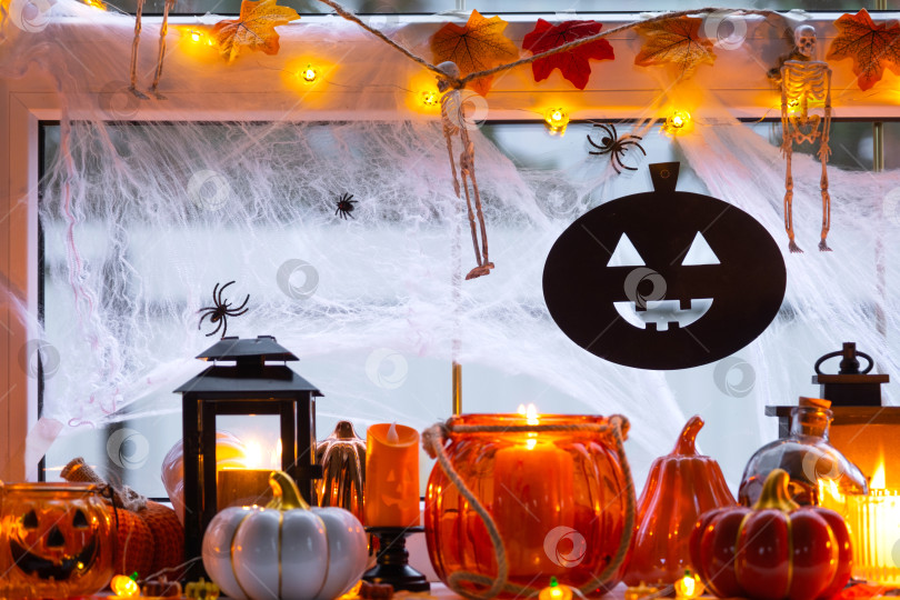 Скачать Праздничный декор дома на подоконнике к Хэллоуину - тыквы, фонарики Джек о, черепа, паутина, пауки, скелеты, свечи и гирлянда - уютное и жуткое настроение фотосток Ozero