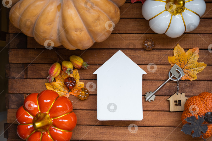 Скачать Уютный макет дома на деревянном фоне из реек с тыквами, осенними листьями, домом и ключами - осеннее настроение, Хэллоуин, жилье, переезд, ипотека, страховка. фотосток Ozero