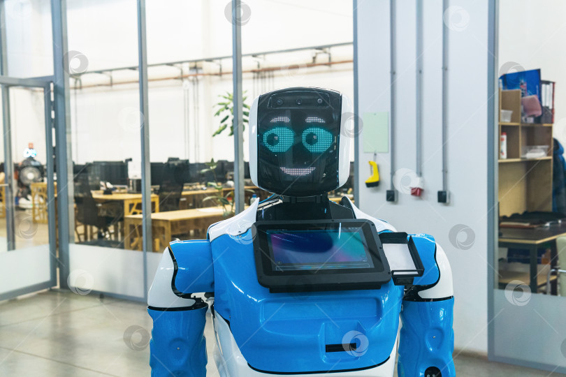 Скачать человекоподобный робот с дружелюбным лицом в интерьере современного офиса фотосток Ozero