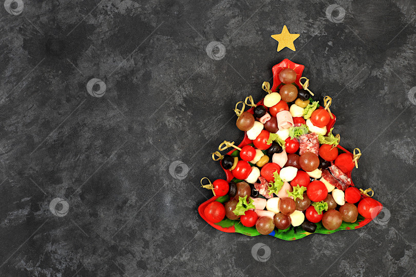 Скачать Рождественские и новогодние блюда, набор закусок для праздничного стола. Тарелка с рождественской елкой из помидоров, паштета, сыра моцарелла, салями, оливок, маслин и винограда на бетонном столе, фотосток Ozero