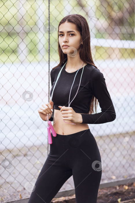 Скачать Портрет молодой красивой девушки в спортивной одежде со скакалкой в руках на улице фотосток Ozero