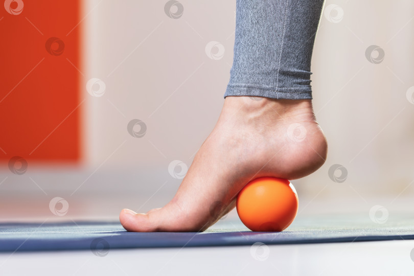 Скачать Миофасциальное расслабление мышц стопы с помощью массажного шарика на коврике в домашних условиях, крупным планом. Концепция на тему предотвращения усталости ног после ношения обуви на высоком каблуке фотосток Ozero