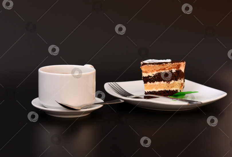 Скачать Кусочек торта из слоеного теста с мятой на тарелке, вилка и чашка горячего кофе на черном фоне. фотосток Ozero