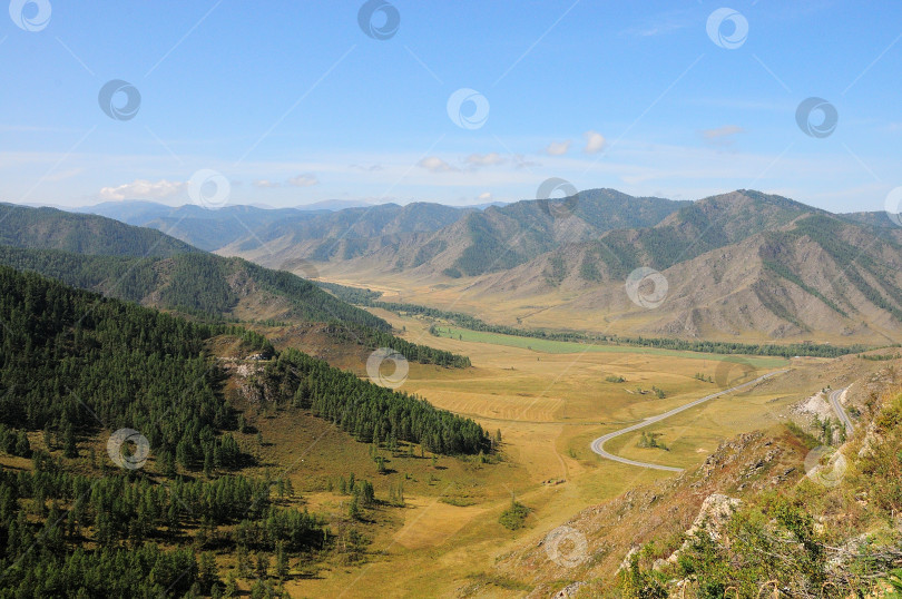 Скачать Вид с вершины живописной долины, окруженной горами, с фрагментов асфальтированной дороги, которая резко поворачивает направо. фотосток Ozero