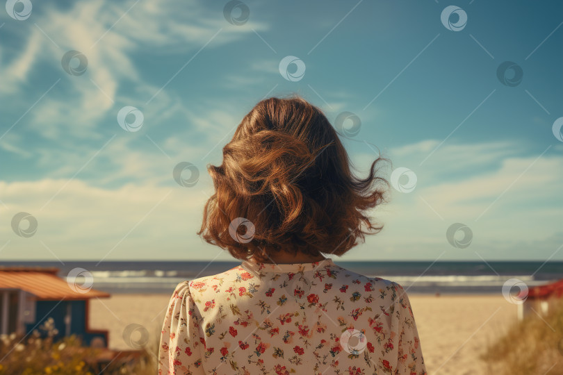 Скачать Летний образ жизни в морском стиле, вид сзади на неузнаваемую молодую женщину со стрижкой каре, одетую в платье и стоящую на пляже на фоне моря в солнечный день. фотосток Ozero
