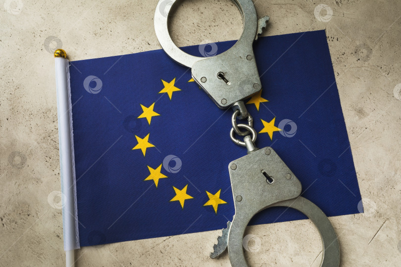 Скачать Флаг ЕС и наручники на абстрактном фоне, концепция преступности в европейском обществе фотосток Ozero