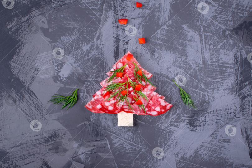 Скачать Канапе "Рождественская елка" с салями на белом хлебе, посыпанном укропом и перцем, на сером столе. Вид сверху. Праздничная закуска. фотосток Ozero