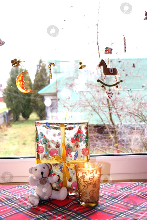 Скачать Новогодний подарок с медвежонком и горящей свечой у сельского окна фотосток Ozero