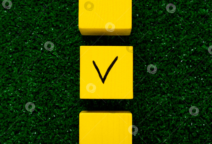 Скачать Три желтых кубика с галочкой на одном на траве. фотосток Ozero