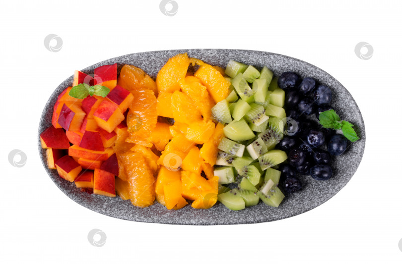 Скачать Ассорти из нарезанных фруктов и ягод, выложенных рядами, напоминающими цвета радуги, на тарелке, выделенной на белом фоне фотосток Ozero
